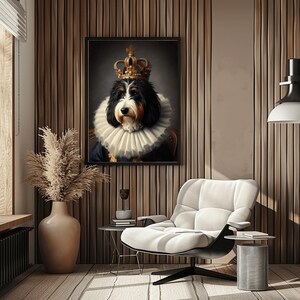 May include: A framed portrait of a dog wearing a crown and a ruffled collar. The dog has black, brown, and white fur. The portrait hangs on a wooden wall above a white armchair and a small side table.