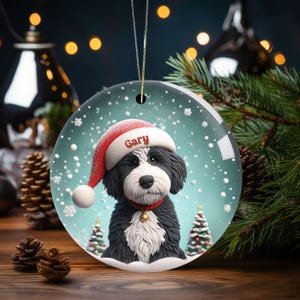 Celebrate the holidays with this adorable Bernedoodle Christmas ornament! Featuring a charming claymation-style Bernie in a Santa hat, surrounded by snowflakes and festive trees, this ornament adds warmth and joy to any holiday decor. For dog lovers!