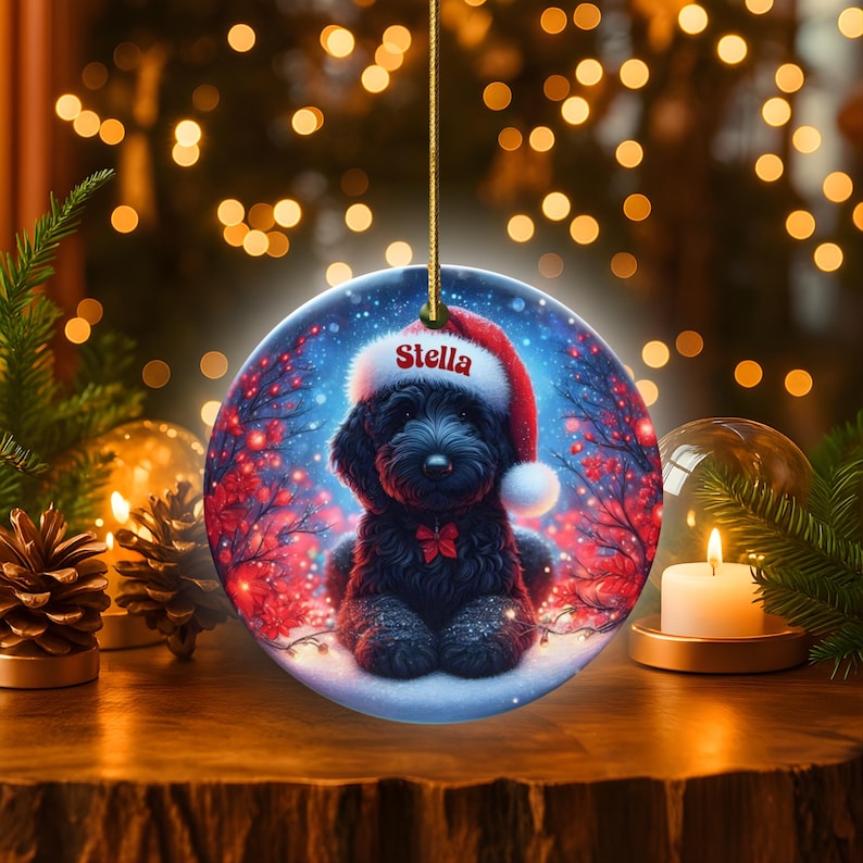 Capture the magic of the season with this adorable black Goldendoodle puppy wearing a festive Santa hat, surrounded by glowing red berries and twinkling snowflakes! Perfect personalized Christmas tree ornament for doodle parents. Add your dog's name (like "Stella") for a heartfelt touch. High-quality ceramic, vibrant print, gold string included. Ideal dog mom/dad gift, stocking stuffer, or memorial keepsake. Handmade holiday charm!