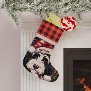 May include: A Christmas stocking featuring a black and white dog with the name "Norman" on a Santa hat. The stocking has a red and black buffalo plaid cuff and is decorated with festive elements. A red and white swirled lollipop is attached.