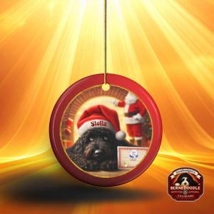 This ceramic ornament features a cute black goldendoodle (or Labradoodle)...Or black bernedoodle dog wearing a Santa hat and being on their best behavior for Santa, surrounded by holiday decorations.  Three inch ceramic dog ornament with a black bernedoodle black golden doodle black goldendoodle dog wearing a santa hat on this cute dog ornament gift.  Perfect ornament for a dog person, dog lover, doodle mom or doodle dad.