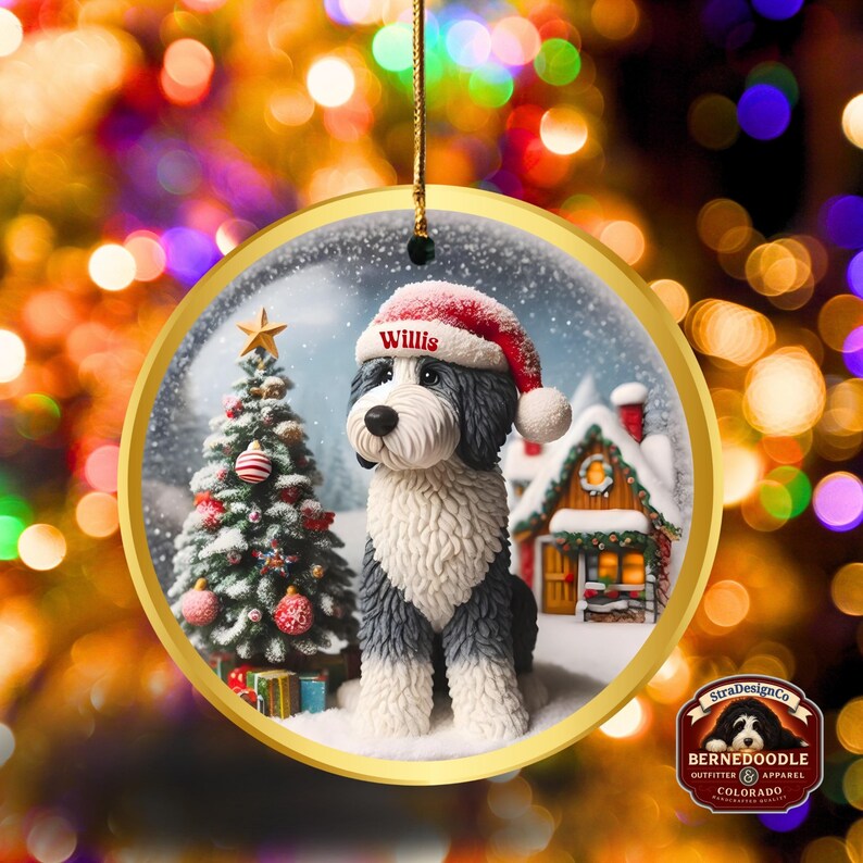 May include: A circular Christmas decoration depicting a Bernedoodle dog in a Santa hat, with the name "Willis". The ornament has a gold edge and a winter scene with a Christmas tree and a snow-covered house.