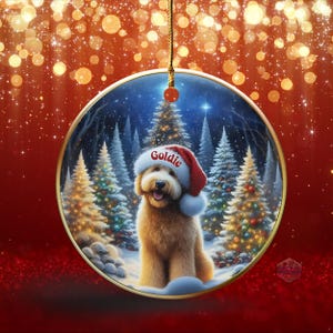 May include: A round Christmas ornament featuring a golden retriever wearing a Santa hat with the name "Goldie" on it. The dog is set against a snowy forest scene with Christmas trees. The ornament hangs from a gold string.