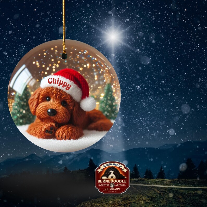 May include: A clear glass Christmas bauble featuring a brown dog wearing a Santa hat with the name "Chippy". The bauble has a gold string for hanging and is set against a snowy, starry background.