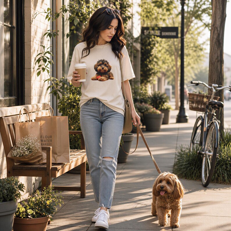 A woman walks her small brown dog on a leash while holding a coffee cup, with a bicycle and potted plants visible in the background.