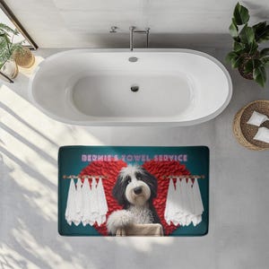 May include: A rectangular teal bath mat featuring a cartoon dog with black and white fur, a red heart, and white towels. The text "BERNIE'S TOWEL SERVICE" is above the dog. The mat is in front of a white bathtub.
