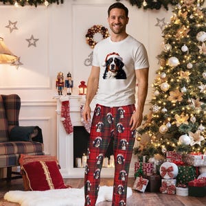 A man seen wearing Men's pajama pants lounge wear personalized Christmas pajama bottoms with Bernese Mountain dogs wearing Santa Hat and their name is on the Santa Hat.  Bernese Mountain Dog dad gear!