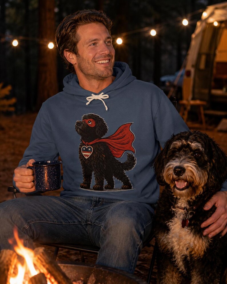 Pu&ograve; includere: Una felpa con cappuccio blu caratterizzata da un'illustrazione grafica di un cane nero che indossa un mantello da supereroe rosso, una mascherina rossa e un emblema a forma di cuore sul petto con un motivo a stelle. La felpa ha lacci bianchi.