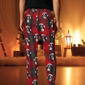 A man seen wearing Men's pajama pants lounge wear personalized Christmas pajama bottoms with Bernese Mountain dogs wearing Santa Hat and their name is on the Santa Hat.  Bernese Mountain Dog dad gear!