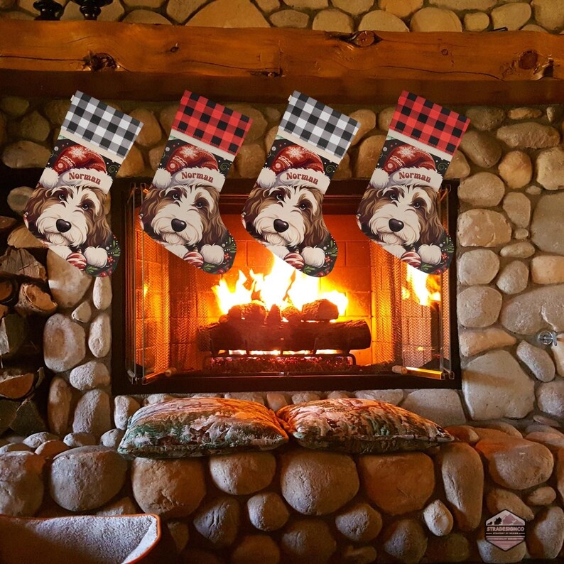 A festive Christmas stocking featuring a whimsical illustrated doodle dog wearing a red Santa hat, surrounded by holiday ornaments and greenery in a warm, detailed Christmas art style. The top of the stocking has a classic red and black buffalo-plaid cuff, and the stocking hangs from a white mantel decorated with evergreen garland and gold ornaments. The stocking design is personalized with your dog’s name, making it a charming and custom holiday décor piece for dog lovers.