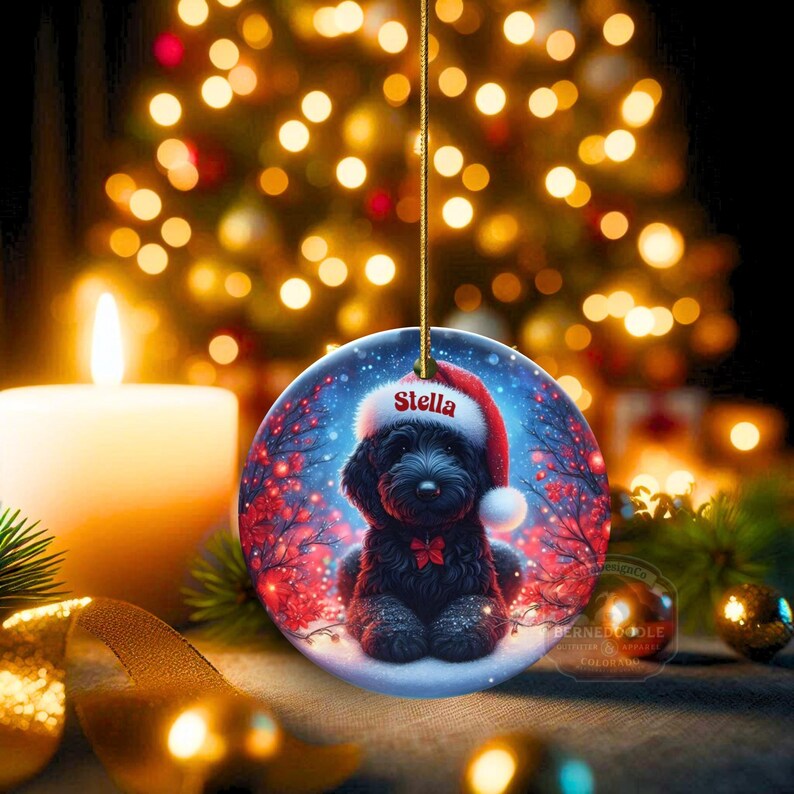 Capture the magic of the season with this adorable black Goldendoodle puppy wearing a festive Santa hat, surrounded by glowing red berries and twinkling snowflakes! Perfect personalized Christmas tree ornament for doodle parents. Add your dog's name (like "Stella") for a heartfelt touch. High-quality ceramic, vibrant print, gold string included. Ideal dog mom/dad gift, stocking stuffer, or memorial keepsake. Handmade holiday charm!