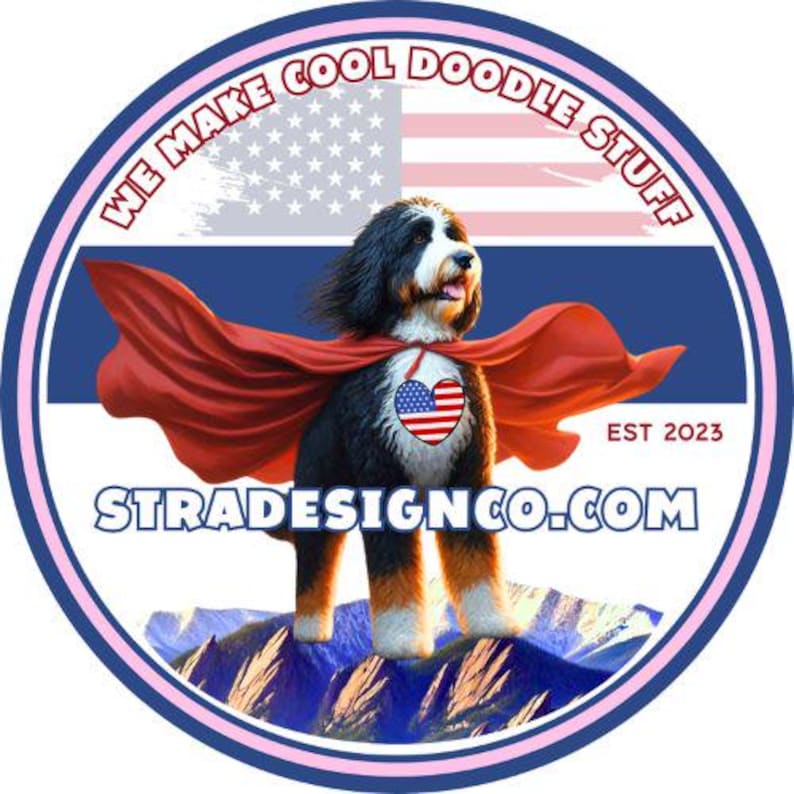 May include: A circular sticker featuring a Bernese Mountain Dog wearing a red cape and a heart-shaped American flag patch. The background shows an American flag and mountains. Text reads WE MAKE COOL DOODLE STUFF, EST 2023, and STRADESIGNCO.COM.