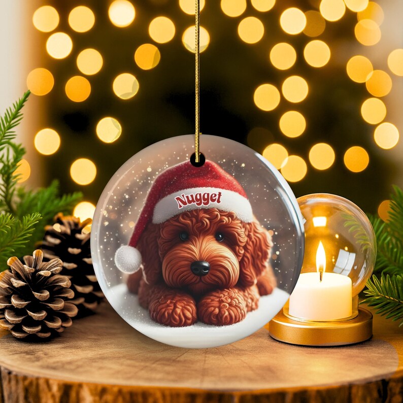 This ceramic ornament features a cute red mini-doodle golden doodle or goldendoodle dog wearing a Santa hat in a snow globe setting, surrounded by holiday decorations. Perfect for adding a festive touch to your Christmas tree or as a thoughtful gift for dog lovers.