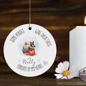 May include: White ceramic ornament with a gold string, featuring a watercolor illustration of a person and a German Shepherd dog. Text reads "Some Heroes Wag Their Tails" and "Wally Forever in My Heart."