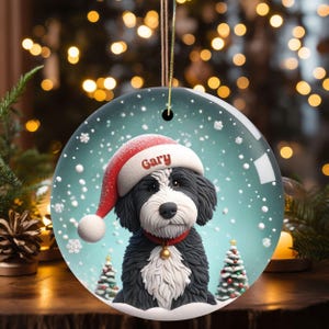 Celebrate the holidays with this adorable Bernedoodle Christmas ornament! Featuring a charming claymation-style Bernie in a Santa hat, surrounded by snowflakes and festive trees, this ornament adds warmth and joy to any holiday decor. For dog lovers!