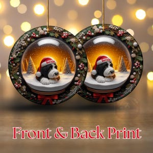 May include: Two round Christmas ornaments featuring a snow globe design with a dog wearing a Santa hat. The ornaments have a black and white dog with the name "Bernie" on the hat, set against a snowy landscape with Christmas trees. The text "Front & Back Print" is at the bottom.