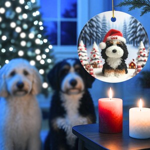Bernedoodle claymation style ornament made of ceramic, hanging by a gold string.  Winter scene featuring a cute, personalized doodle dog with personalized name on santa hat.  Perfect gift for Bernedoodle Dog Lovers and Pet Enthusiasts.