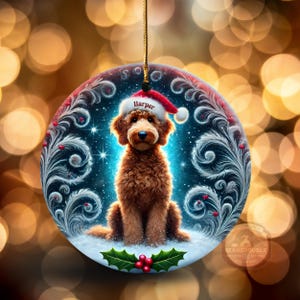 Round holiday ornament features a goldendoodle in a Santa hat labeled “Harper,” seated on snowy ground surrounded by icy swirl artwork, glowing stars, and holly berries. The soft golden bokeh lights in the background create a magical Christmas feel. Ideal for personalizing your tree or gifting to doodle families.