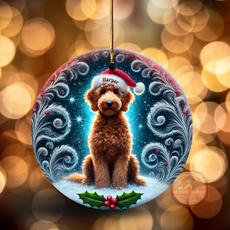 Round holiday ornament features a goldendoodle in a Santa hat labeled “Harper,” seated on snowy ground surrounded by icy swirl artwork, glowing stars, and holly berries. The soft golden bokeh lights in the background create a magical Christmas feel. Ideal for personalizing your tree or gifting to doodle families.