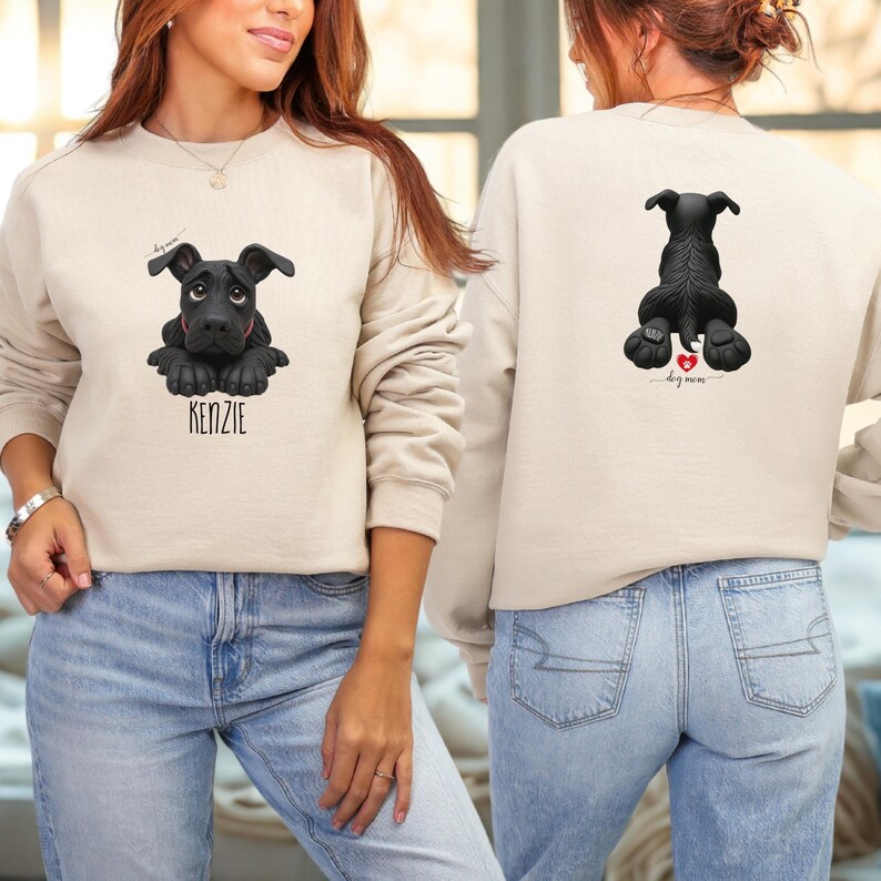 Puede incluir: Sudadera beige con un gr&aacute;fico de perro negro en la parte delantera y trasera. El gr&aacute;fico frontal incluye el nombre del perro, "KENZIE". El gr&aacute;fico trasero muestra la parte trasera del perro con un coraz&oacute;n y las palabras "dog mom".