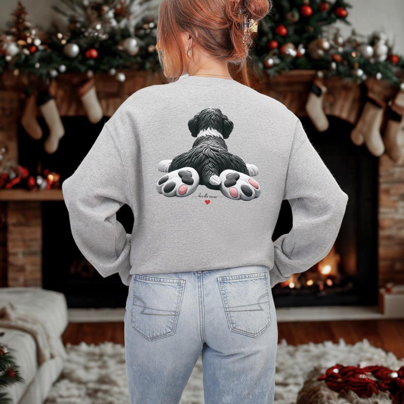 K&ouml;nnte beinhalten: Ein hellgraues Sweatshirt mit einem schwarz-wei&szlig;en Hunde-Motiv auf dem R&uuml;cken. Der Hund liegt mit sichtbaren Pfoten, und die Grafik enth&auml;lt den Text "hello mom" mit einem kleinen roten Herz. Das Sweatshirt wird mit hellblauen Jeans getragen.