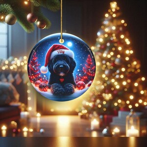 This festive ornament features an adorable black doodle wearing a Santa hat, surrounded by soft glowing holiday lights and rich red Christmas tones. The warm lighting highlights the dog’s fluffy black fur, giving the design a bright, cheerful look that stands out on any tree. A perfect personalized keepsake for anyone who loves black doodles and joyful holiday décor.