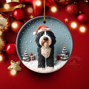May include: A round Christmas ornament featuring a Bernedoodle dog wearing a Santa hat with the name "Willy". The dog is set in a snowy scene with Christmas trees and gifts. The ornament is hanging against a red background with Christmas decorations.