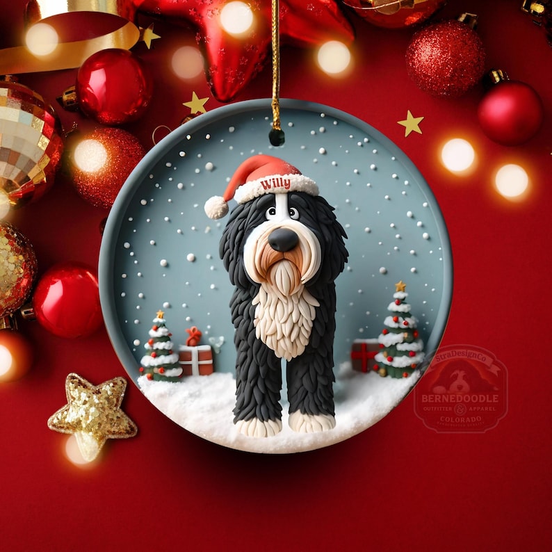 May include: A round Christmas ornament featuring a Bernedoodle dog wearing a Santa hat with the name "Willy". The dog is set in a snowy scene with Christmas trees and gifts. The ornament is hanging against a red background with Christmas decorations.