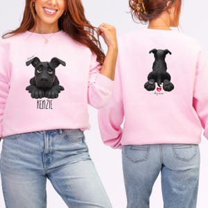 Puede incluir: Sudadera rosa claro con un dise&ntilde;o de perro negro en la parte delantera y trasera. El dise&ntilde;o frontal incluye el nombre "KENZIE" en texto blanco. El dise&ntilde;o trasero presenta un coraz&oacute;n y las palabras "dog mom".