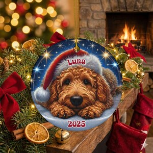 A ceramic ornament of a goldendoodle dog wearing a Santa hat, personalized with the dog's name and the year.  Gorgeously placed in a warm background with candles and Christmas lights.