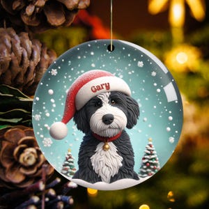 Celebrate the holidays with this adorable Bernedoodle Christmas ornament! Featuring a charming claymation-style Bernie in a Santa hat, surrounded by snowflakes and festive trees, this ornament adds warmth and joy to any holiday decor. For dog lovers!