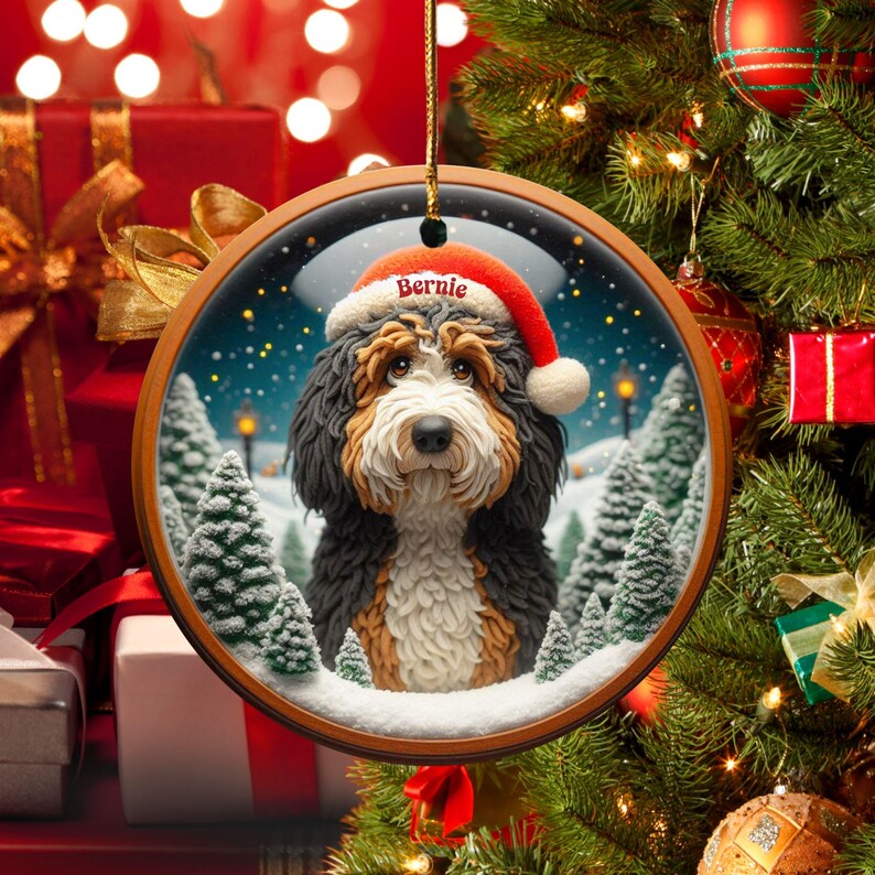 Op de afbeelding: Ronde kerstversiering met een Bernedoodle-hond met een kerstmuts met de naam "Bernie". De versiering heeft een houten frame en een winterse achtergrond met besneeuwde bomen en een sterrenhemel. Een feestelijke vakantieversiering.