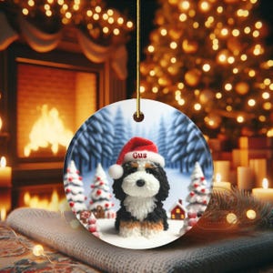 Bernedoodle claymation style ornament made of ceramic, hanging by a gold string.  Winter scene featuring a cute, personalized doodle dog with personalized name on santa hat.  Perfect gift for Bernedoodle Dog Lovers and Pet Enthusiasts.