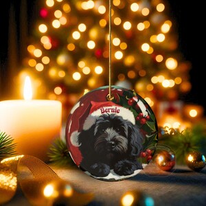 A black bernedoodle dog wearing a santa hat that is personalized with their name on it in this adorable Ceramic ornament!  Design appears on the front and the back of this doodle dog ornament!