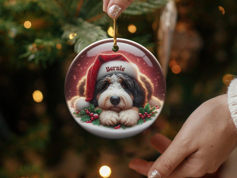 Personalize your holiday decor with this charming Bernedoodle Christmas ornament! Featuring a cute Bernedoodle in a festive Santa hat and customizable name, this round ornament adds warmth and joy to any tree. Perfect for dog lovers and unique gifts!