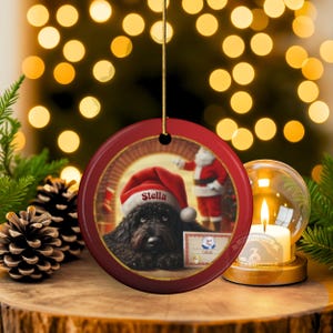 This ceramic ornament features a cute black goldendoodle (or Labradoodle)...Or black bernedoodle dog wearing a Santa hat and being on their best behavior for Santa, surrounded by holiday decorations.  Three inch ceramic dog ornament with a black bernedoodle black golden doodle black goldendoodle dog wearing a santa hat on this cute dog ornament gift.  Perfect ornament for a dog person, dog lover, doodle mom or doodle dad.