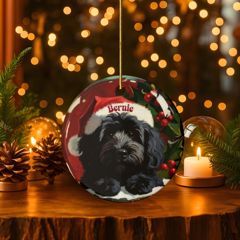 A black bernedoodle dog wearing a santa hat that is personalized with their name on it in this adorable Ceramic ornament!  Design appears on the front and the back of this doodle dog ornament!