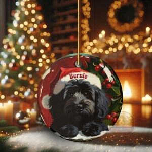 A black bernedoodle dog wearing a santa hat that is personalized with their name on it in this adorable Ceramic ornament!  Design appears on the front and the back of this doodle dog ornament!