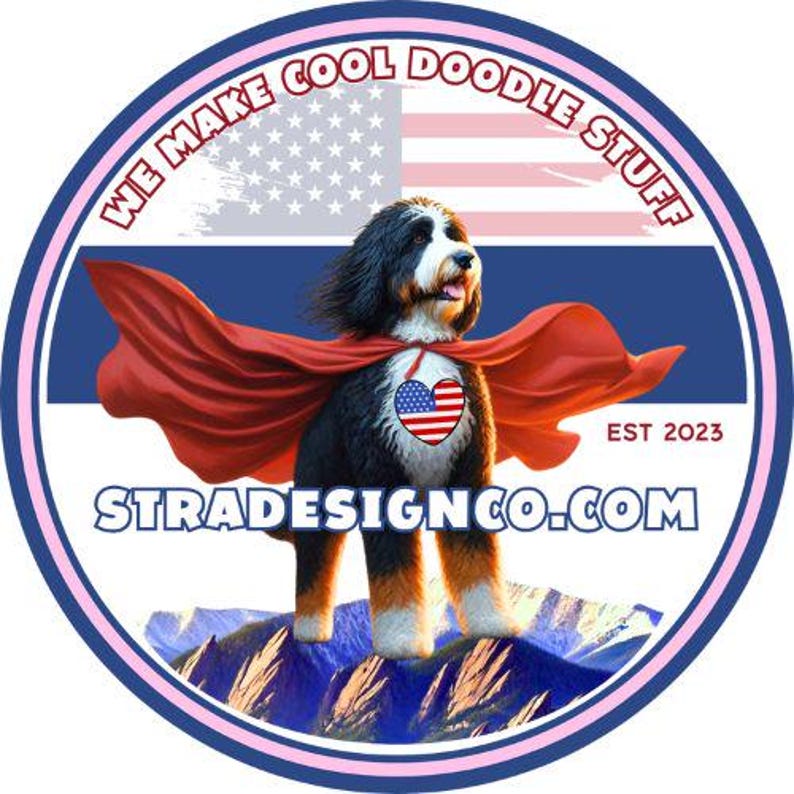 May include: A round sticker featuring a dog wearing a red cape and a heart-shaped emblem with the American flag. The background includes the American flag and the text "WE MAKE COOL DOODLE STUFF" and "STRADESIGNCO.COM".