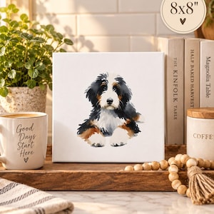 Puede incluir: Un lienzo cuadrado blanco con una ilustraci&oacute;n en acuarela de un cachorro de boyero de Berna con pelaje negro, blanco y marr&oacute;n. El lienzo tiene la etiqueta 8x8 pulgadas en la esquina superior derecha, lo que indica sus dimensiones.