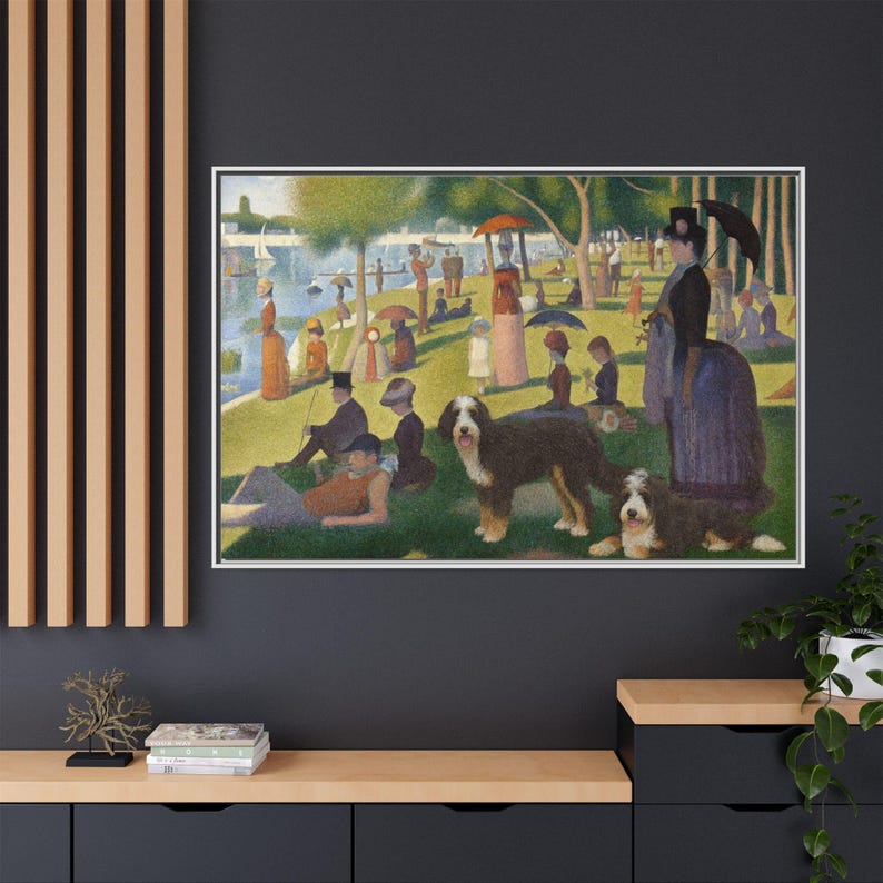 May include: Framed print of a pointillism painting depicting a park scene with people, dogs, and a lake. The artwork features a white frame and is displayed on a dark gray wall. The painting showcases a vibrant use of color and detail.