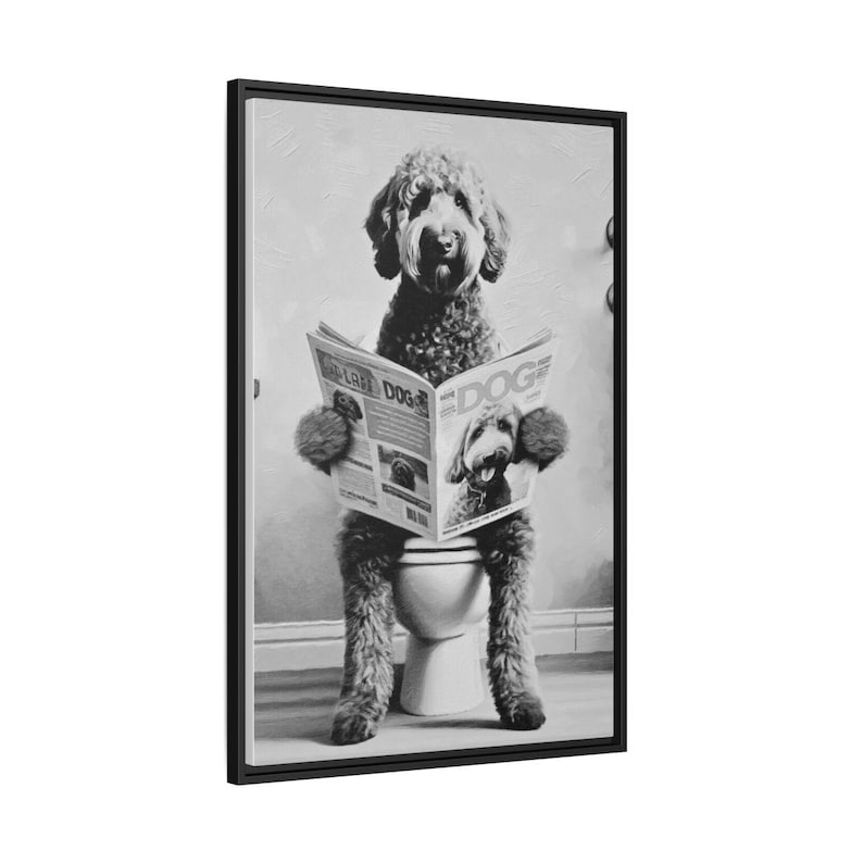 May include: A black and white framed wall art print featuring a curly-haired dog sitting on a toilet while reading a newspaper titled DOG. The dog has a shaggy coat and is holding the open newspaper with both front paws in a vertical orientation.
