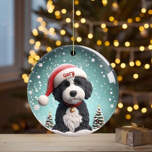 Celebrate the holidays with this adorable Bernedoodle Christmas ornament! Featuring a charming claymation-style Bernie in a Santa hat, surrounded by snowflakes and festive trees, this ornament adds warmth and joy to any holiday decor. For dog lovers!