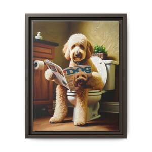 May include: A framed canvas print shows a golden doodle dog on a toilet, reading a magazine with the word "Dog" on the cover. The dog is in a bathroom setting with a toilet, toilet paper, and a small plant.