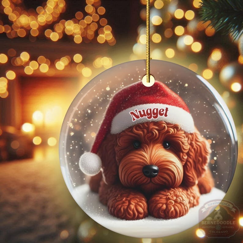 This ceramic ornament features a cute red mini-doodle golden doodle or goldendoodle dog wearing a Santa hat in a snow globe setting, surrounded by holiday decorations. Perfect for adding a festive touch to your Christmas tree or as a thoughtful gift for dog lovers.