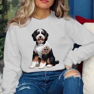 A woman wearing a white sweatshirt with a graphic of a dog on it.