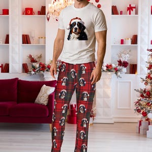 A man seen wearing Men's pajama pants lounge wear personalized Christmas pajama bottoms with Bernese Mountain dogs wearing Santa Hat and their name is on the Santa Hat.  Bernese Mountain Dog dad gear!