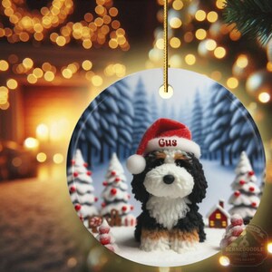 Bernedoodle claymation style ornament made of ceramic, hanging by a gold string.  Winter scene featuring a cute, personalized doodle dog with personalized name on santa hat.  Perfect gift for Bernedoodle Dog Lovers and Pet Enthusiasts.