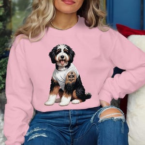A woman wearing a pink sweatshirt with a graphic of a dog on it.