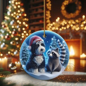 A 3-inch double-sided ceramic Christmas ornament featuring an adorable claymation-style Bernedoodle wearing a red Santa hat personalized  sitting beside a cute raccoon under a snowy winter night sky. The ornament has crisp detailing, soft blue tones, and a warm Christmas glow in the blurred background. Perfect for Bernedoodle lovers, handmade Christmas gift shoppers. High-quality ceramic with vibrant colors, ideal for tree decorating, pet memorial ornaments, or festive seasonal displays.
